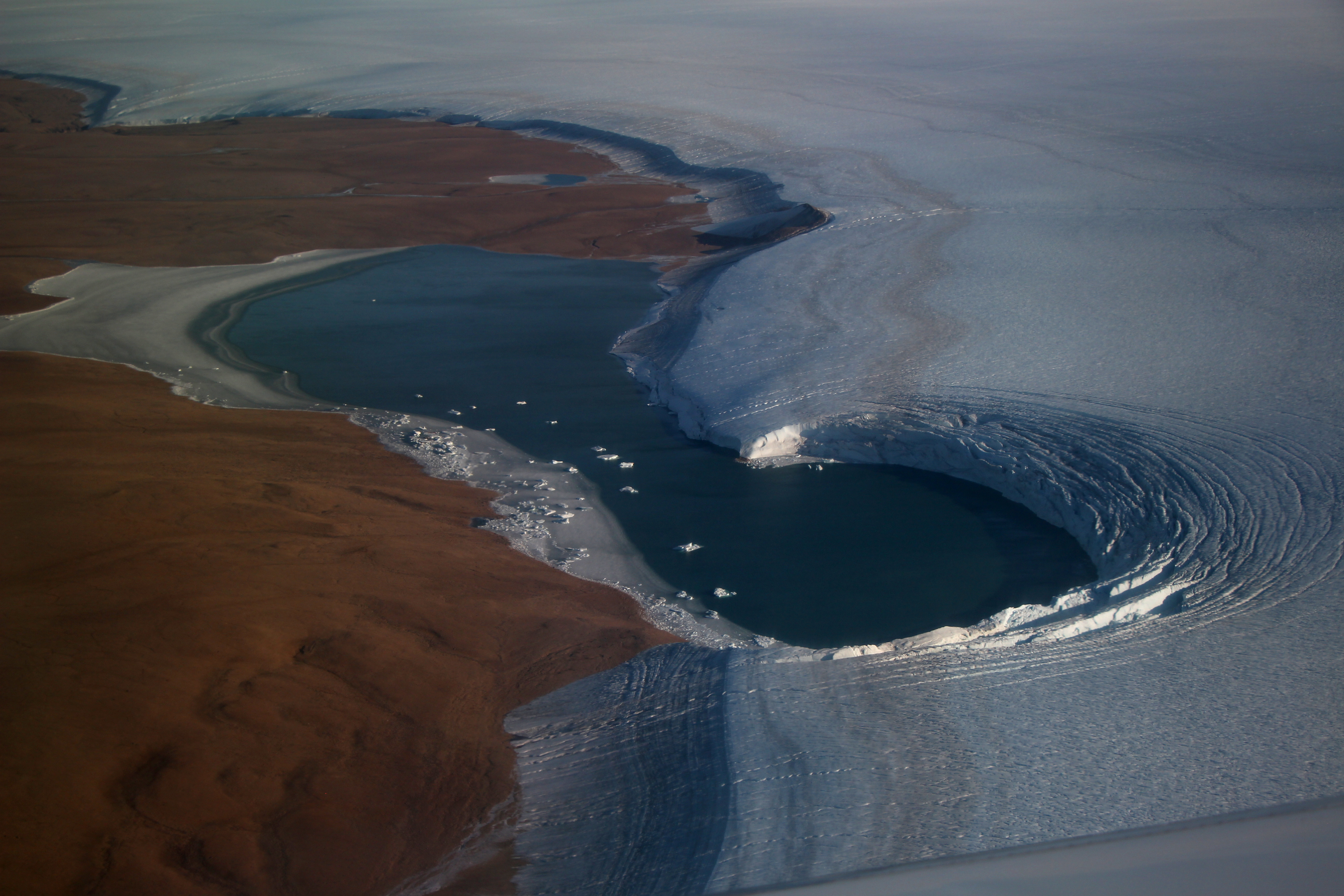 This picture along the NW coast of Greenland captures the island-wide thinning and melting with basal ice (in this case ~55,000 years old) directly on top of the landscape and the gradation along the slope of the ice layers that lead to the surface of the ice sheet today.  The banding, or stratigraphy is marked by major dust depositional periods (surrogates for global drought & warm periods) that are validated by independent water isotope (δ18O, δ2H, and d-excess) measurements (Welker’s lab)